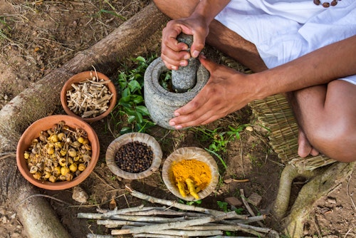 A man using turmeric and other herbs to prepare traditional medicine for treating prostate cancer