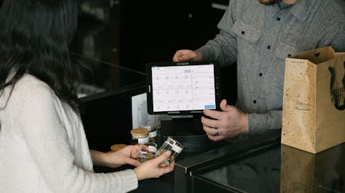 Image of a lady purchasing some products from a store and making payment with an app