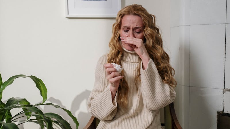 A woman having a runny nose due to an allergic reaction