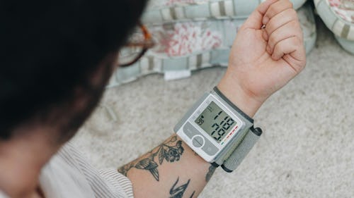 Image of a man with tattoos checking his blood sugar level using an at-home glucometer device 