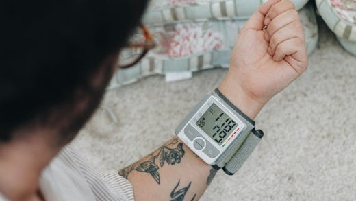 Image of a man with tattoos checking his blood sugar level using an at-home glucometer device 