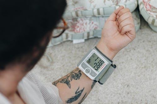 Image of a man with tattoos checking his blood sugar level using an at-home glucometer device 