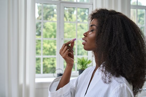 Picture of a Black woman with long hair on a white robe taking a pill