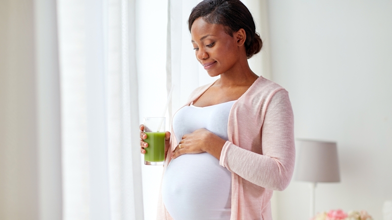 pregnant woman carrying a glass of green tea smoothie for burning belly fat