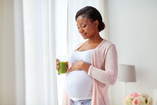 pregnant woman carrying a glass of green tea smoothie for burning belly fat