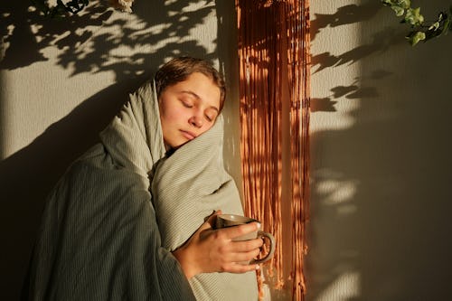 A lady receiving sun outside her porch with a cup of coffee in hands