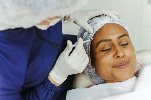 A woman getting a botox (botulinum) injection on her forehead