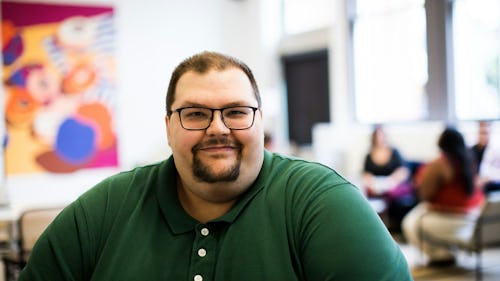 Image of an overweight man at work wearing an eyeglass and smiling