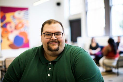 Image of an overweight man at work wearing an eyeglass and smiling