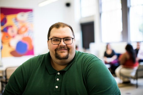 Image of an overweight man at work wearing an eyeglass and smiling