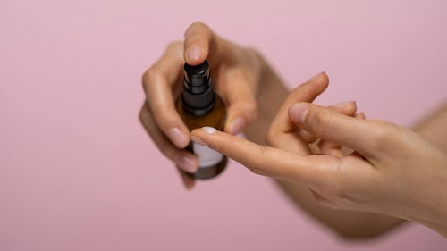 Image of a woman applying drops of lubricant from a bottle to the tips of her fingers