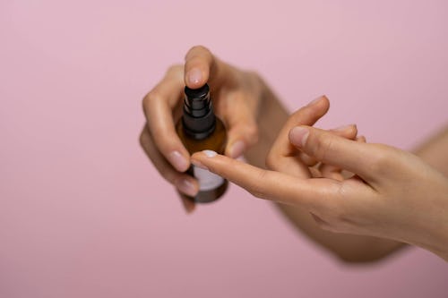 Image of a woman applying drops of lubricant from a bottle to the tips of her fingers