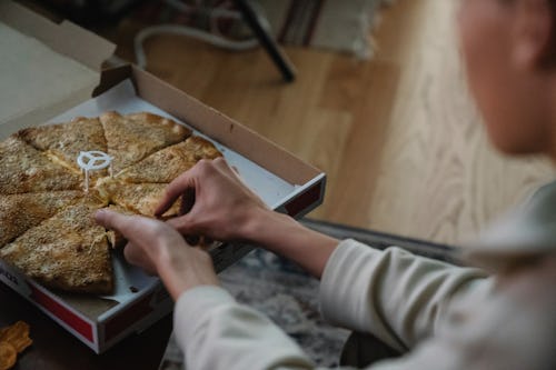 A woman snacking on Pizza late at night