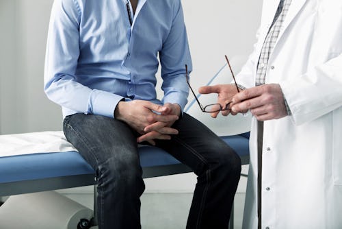 Doctor speaking to a male patient after physical examination on a hospital bed