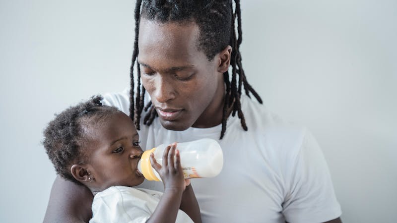 Man feeding a baby with a palm oil-based infant formula