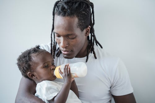 Man feeding a baby with a palm oil-based infant formula