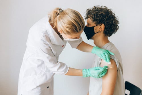 Image of a nurse wearing hand gloves a man injection on arm