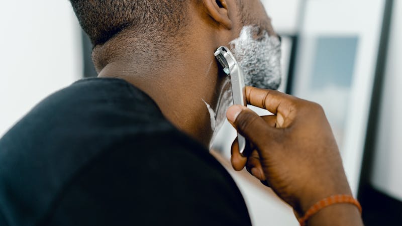 A man shaving his beards in the direction of hair growth to prevent razor bumps