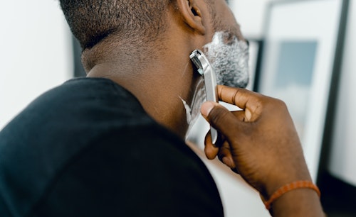 A man shaving his beards in the direction of hair growth to prevent razor bumps