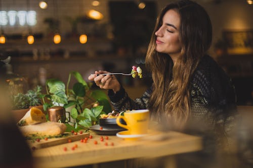 A woman eating food alone in a table, enjoying the meal and savoring the moment