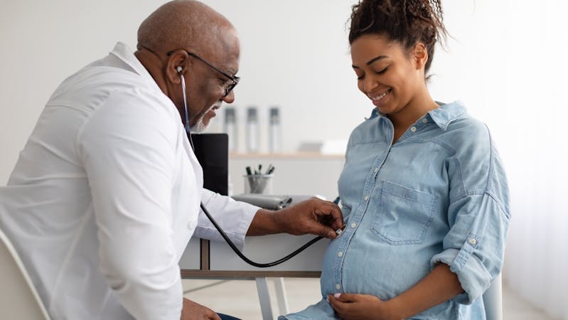 A reproductive endocrinologist examining a pregnant black woman after IVF