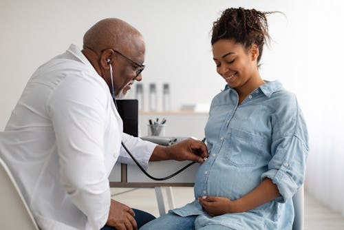 A reproductive endocrinologist examining a pregnant black woman after IVF