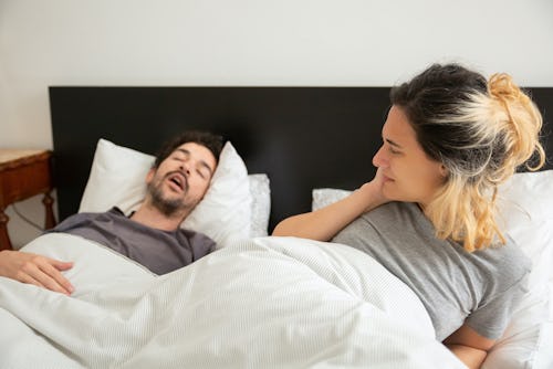 A man snoring while sleeping beside his wife