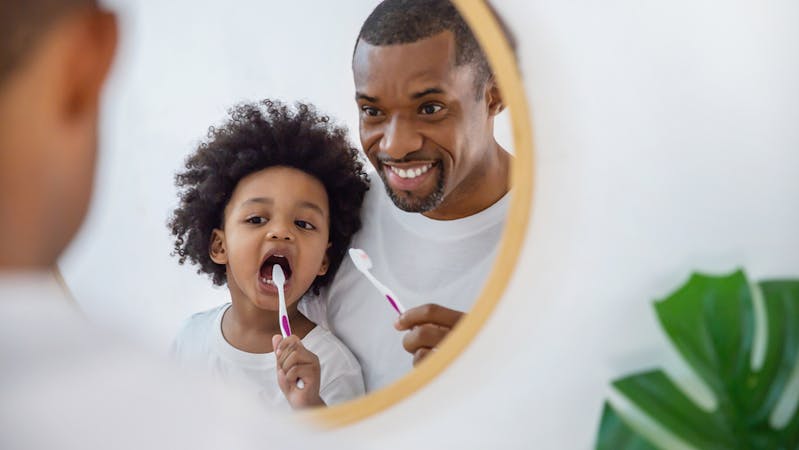Man brushing teeth with his child