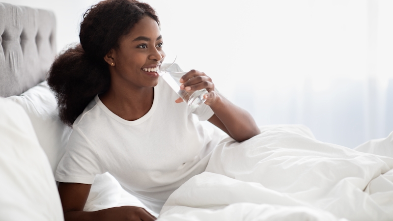Black woman drinking water in bed after sex