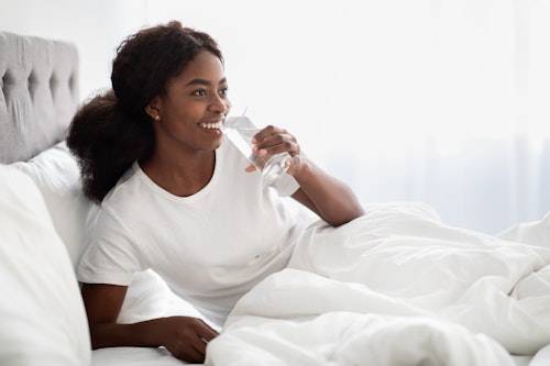 Black woman drinking water in bed after sex