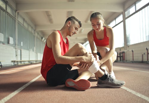 A White girl using the R.I.C.E. therapy to treat a White boy with a minor leg injury