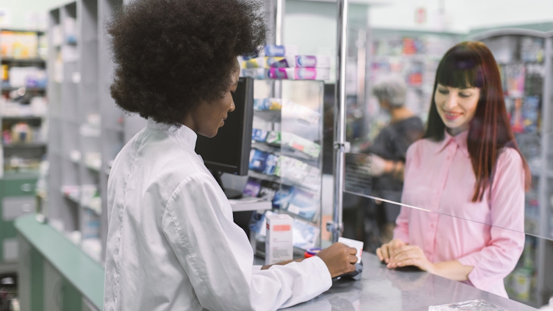 A white girl buying medicine from a pharmacist at a pharmacy store