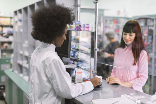 A white girl buying medicine from a pharmacist at a pharmacy store