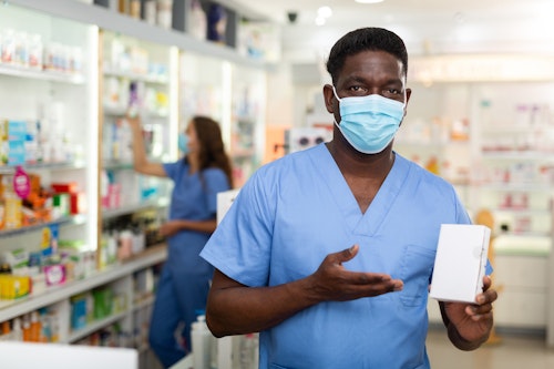 Black pharmacist in a pharmacy shop holding a postinor-2 pack