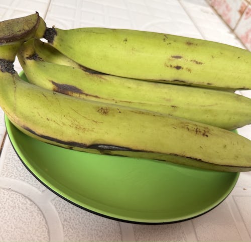 A bunch of unriple plantain placed on a green plate