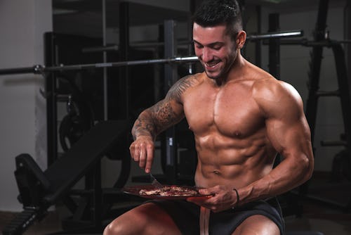 An athletic bodybuilder eating in the gym