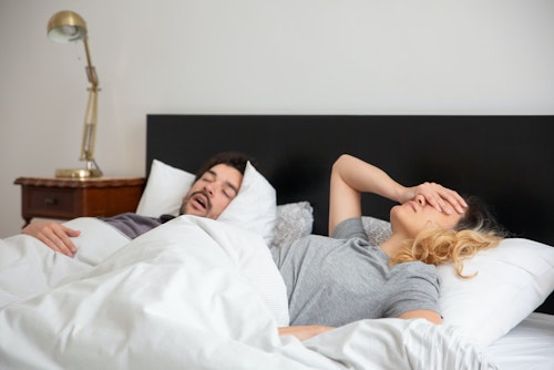 A man snoring while sleeping with his wife lying by his side