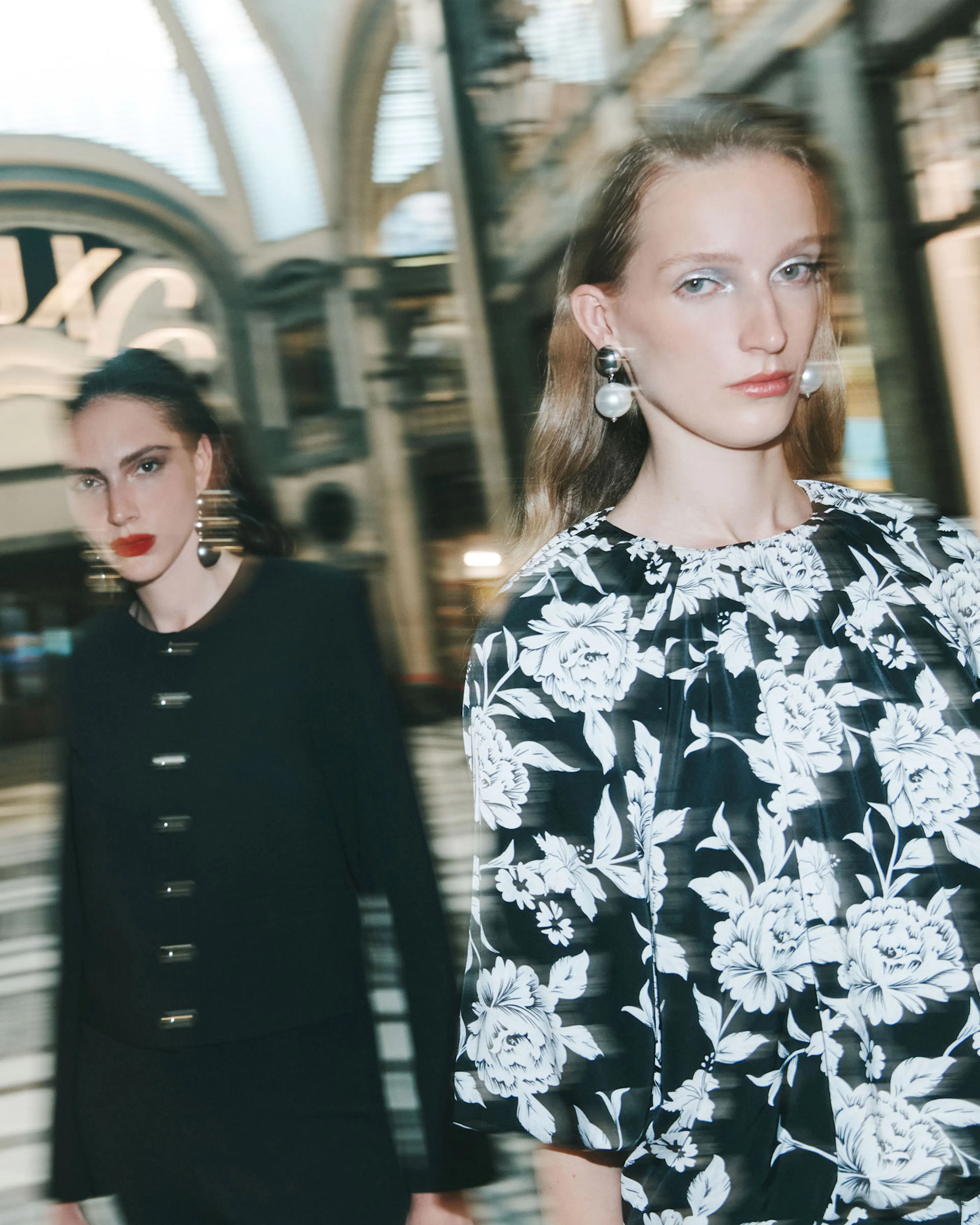 Due ragazze sfocate in una galleria elegante vestite Calliope