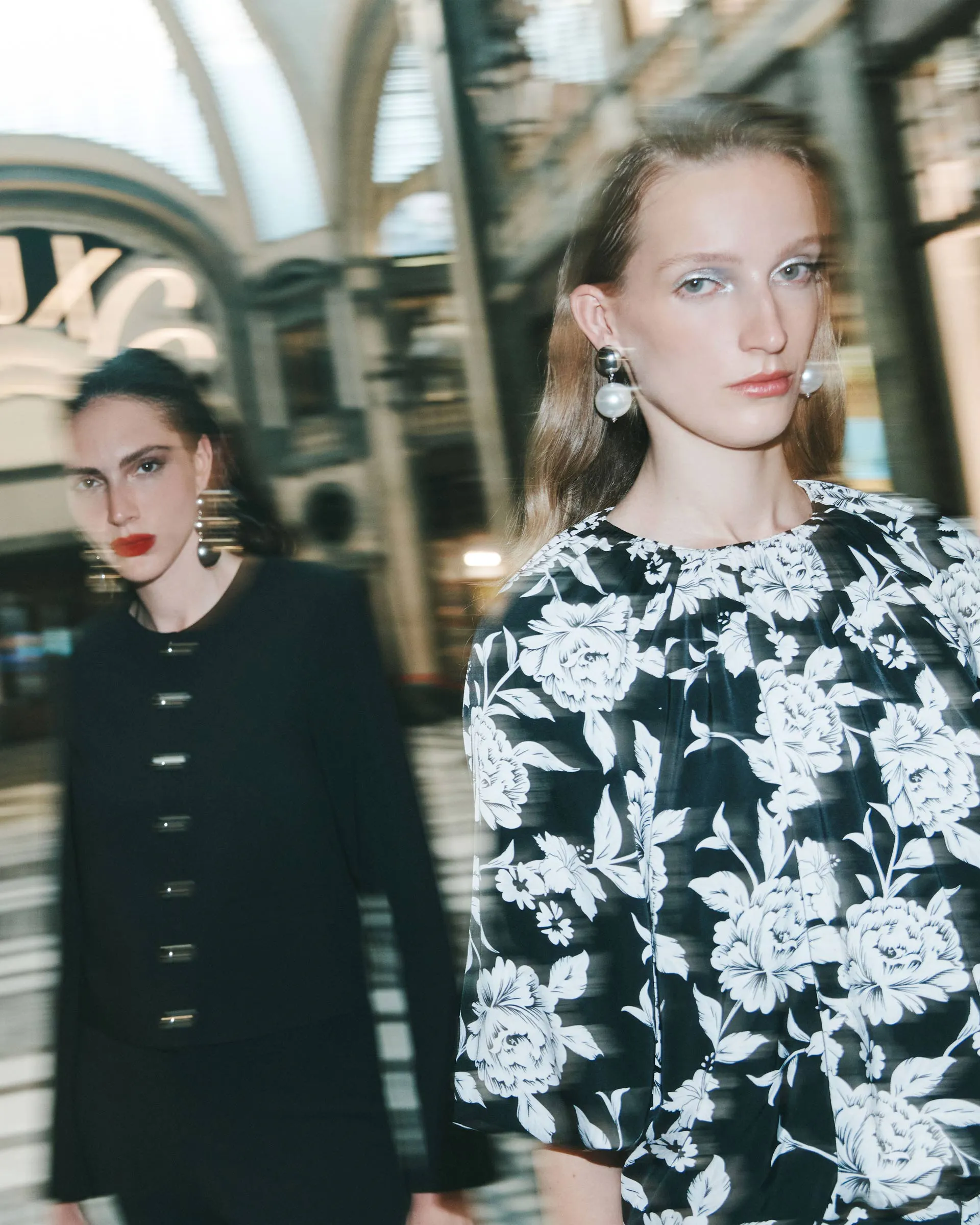 Due ragazze sfocate in una galleria elegante vestite Calliope