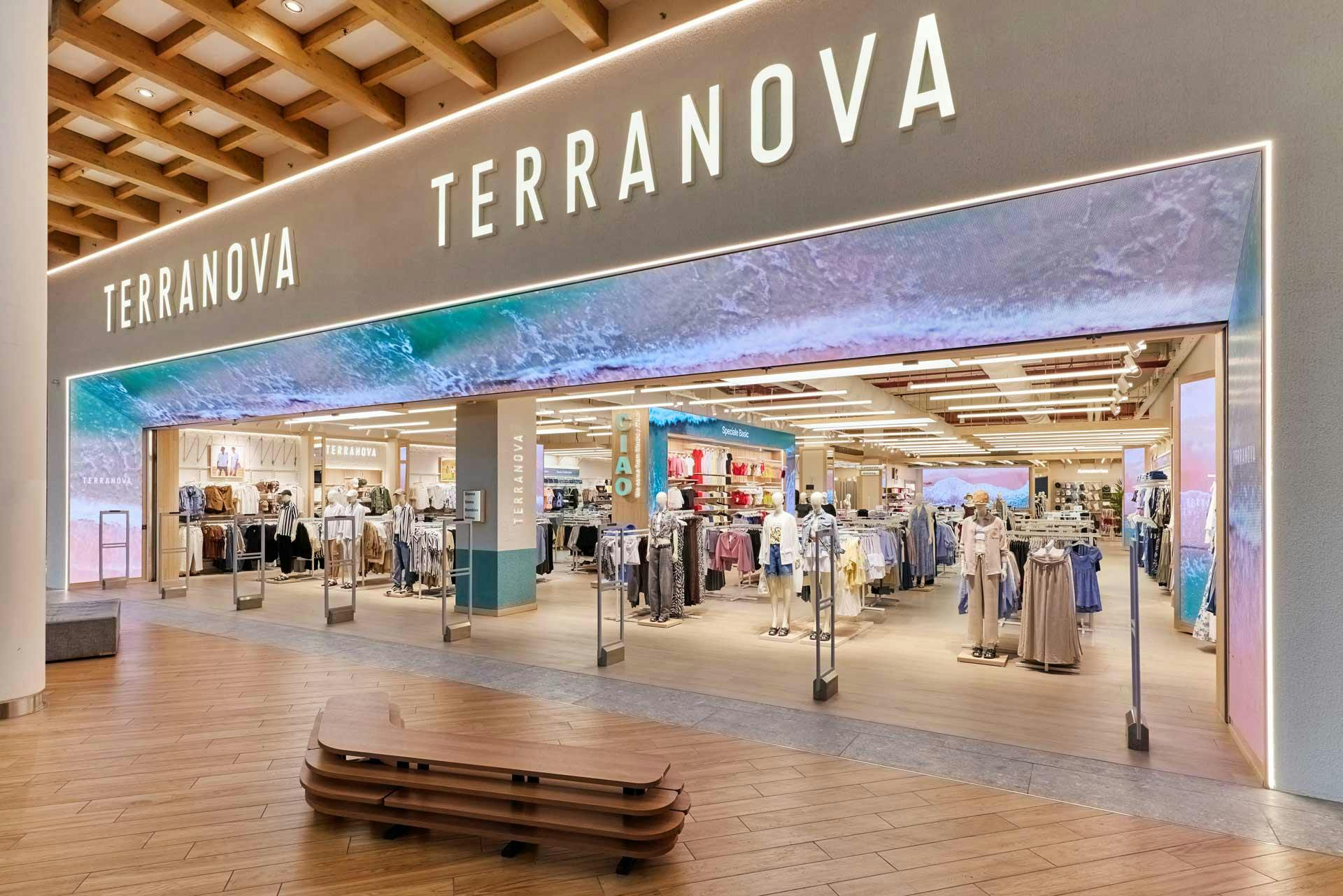 Ingresso negozio Terranova in centro commerciale con insegna illuminata, soffitto a cassettoni in legno e vista dell'interno del punto vendita