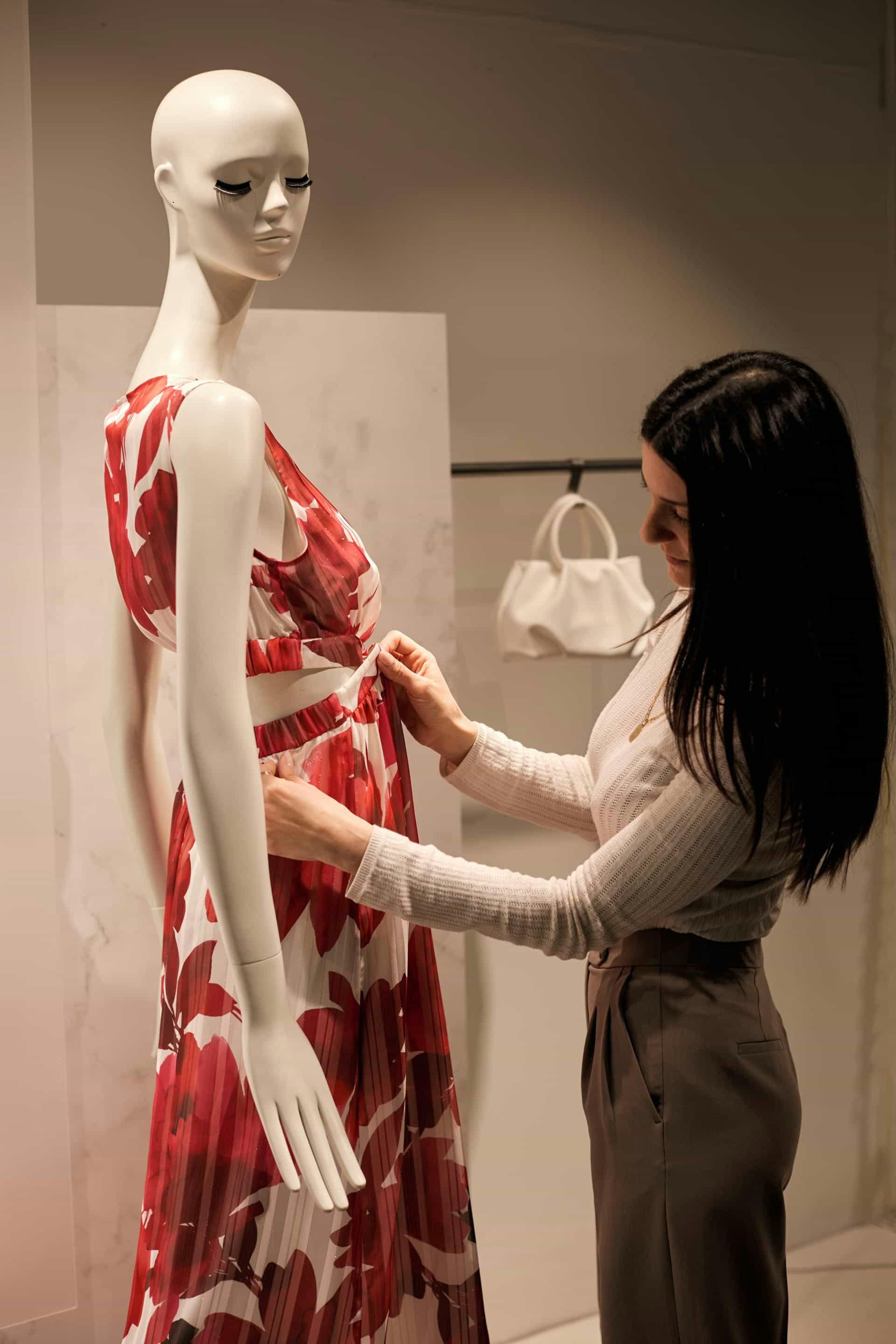 Donna in negozio aggiusta un ambito rosso su un manichino