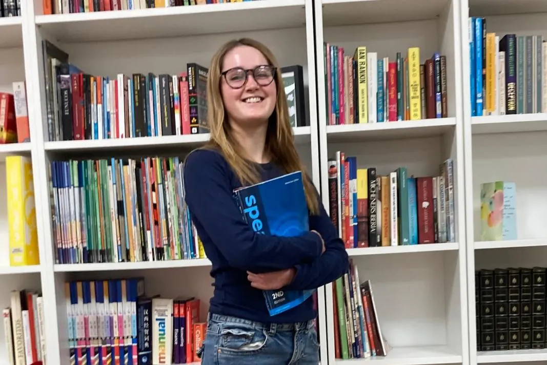 Millie holding a coursebook in the TEFL Iberia library in Barcelona