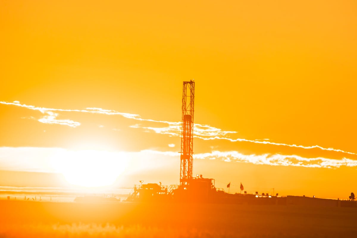An oil rig backlit by a bright sunset.