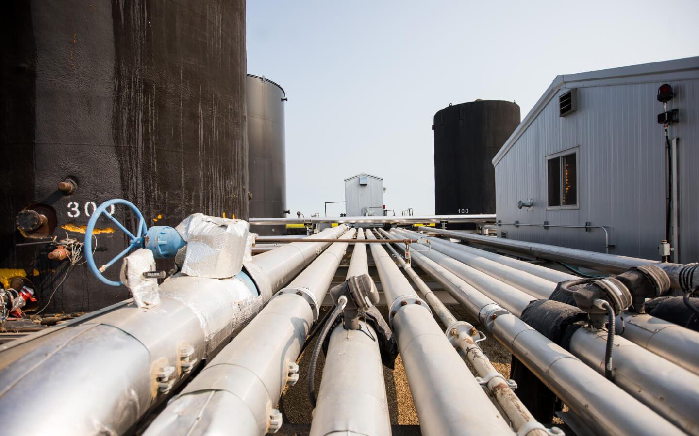 Large oil pipes, lying in parallel on the ground.