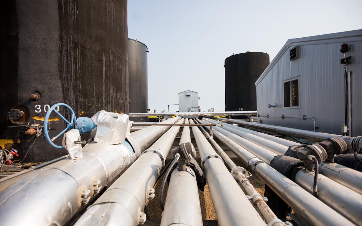 Large oil pipes, lying in parallel on the ground.