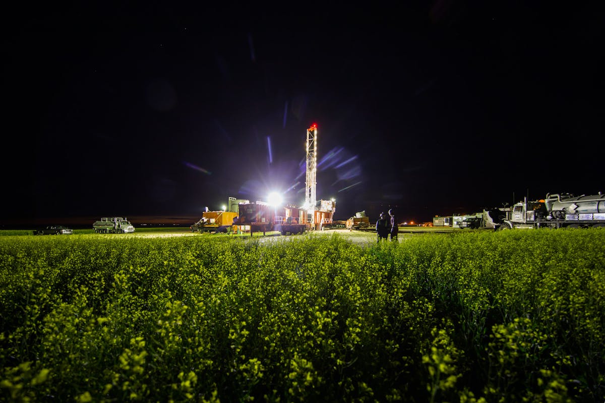An oil rig at night, backlit by a bright light.