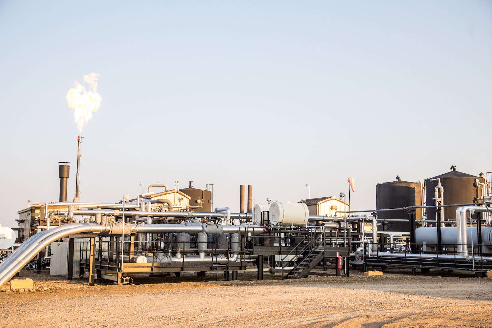 Oil machinery burning off gas under a blue sky.