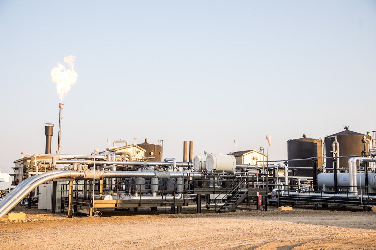 Oil machinery burning off gas under a blue sky.