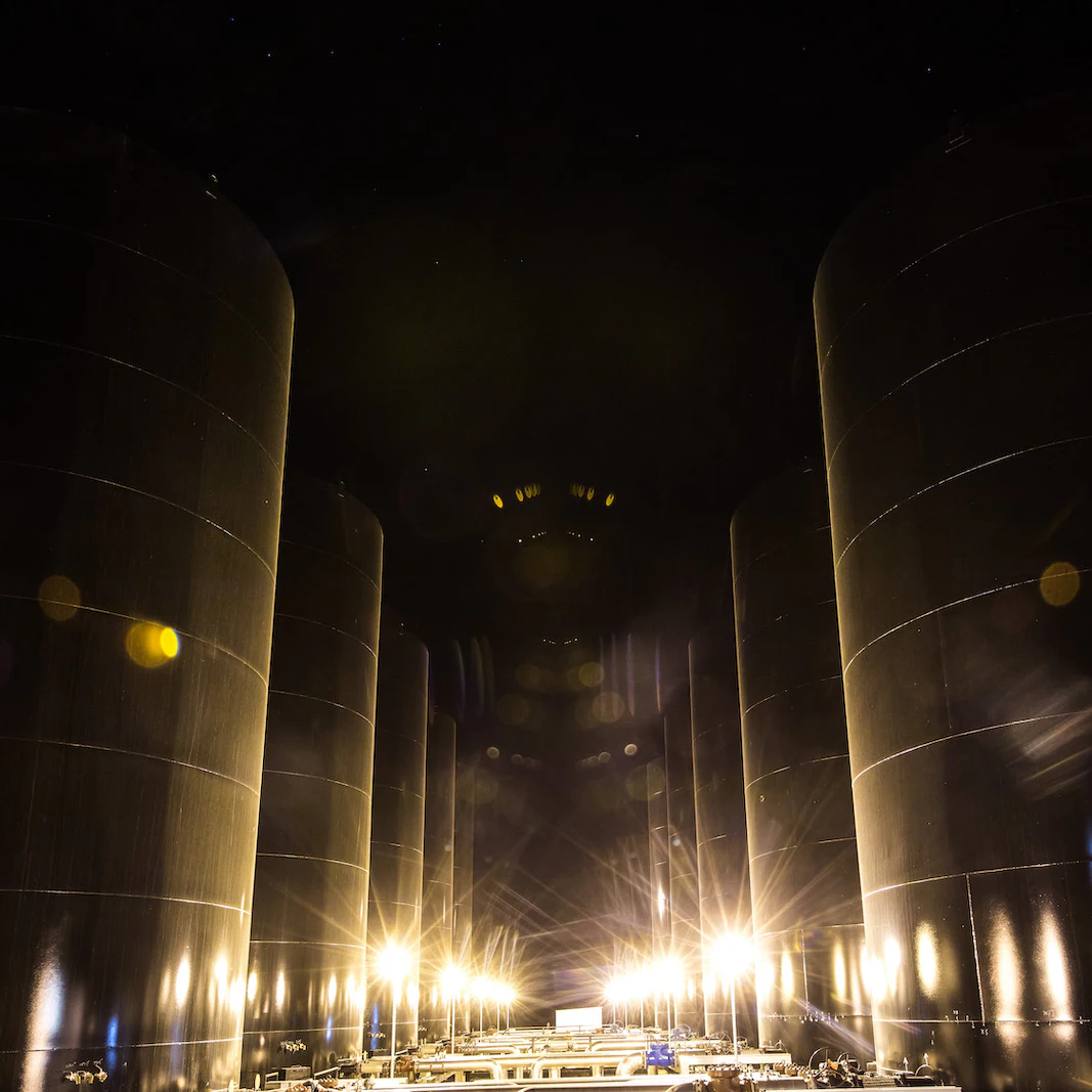 Oil drums at night, lit from the bottom by bright lights.