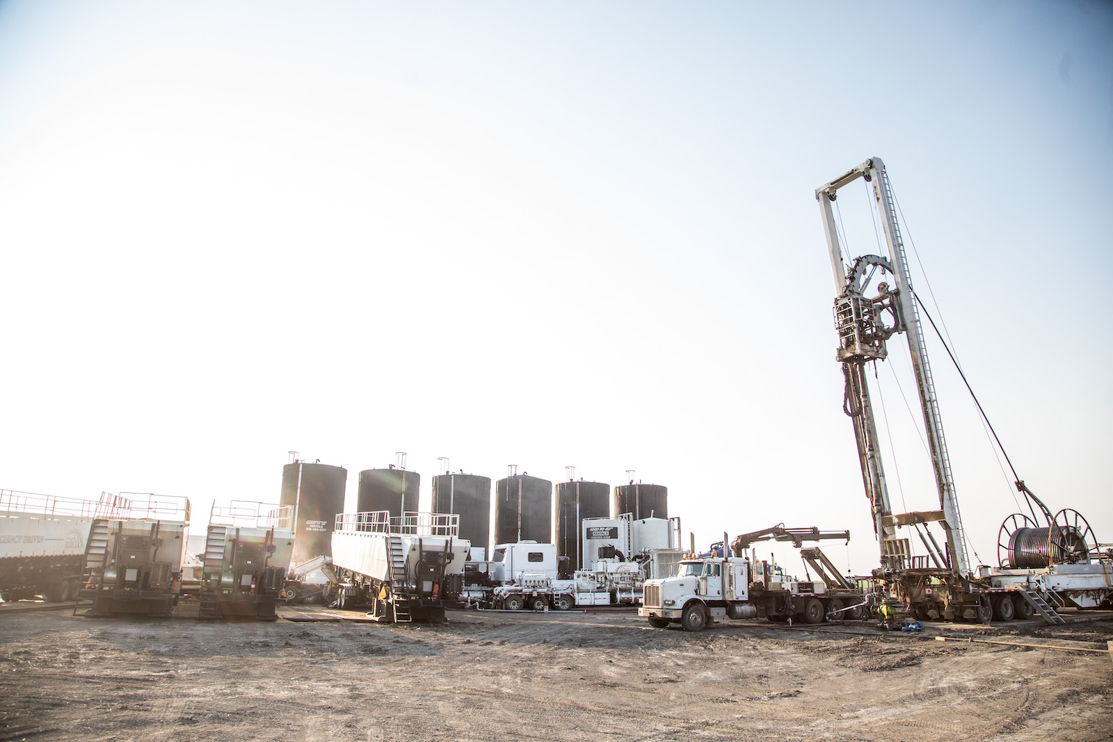 Oil machinery and trucks, under a bright sky.